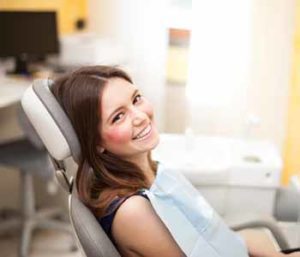 Indianapolis Dental Implants Treatment - Young lady is sitting on the dentist chair, for checking her teeth